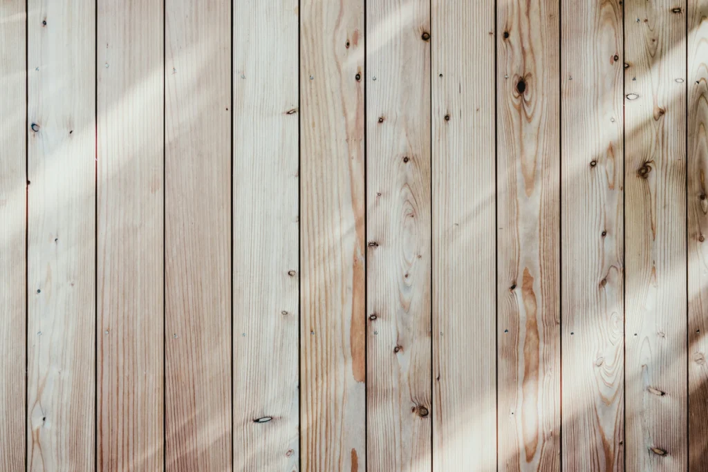 Sunlight casts diagonal shadows on a light wooden plank wall.