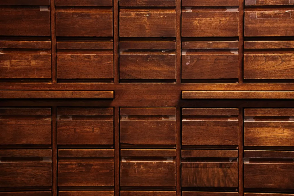 Wooden wall of vertical mailboxes with closed slots and a dark finish.