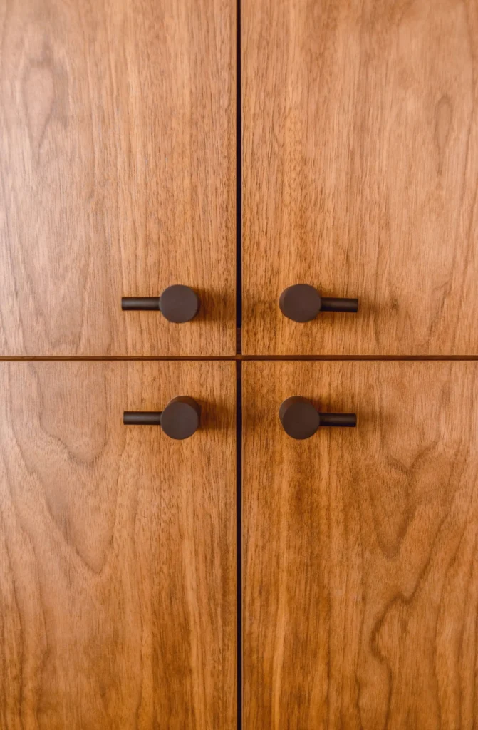 Close-up of four wooden cabinet doors with circular dark handles, arranged symmetrically.