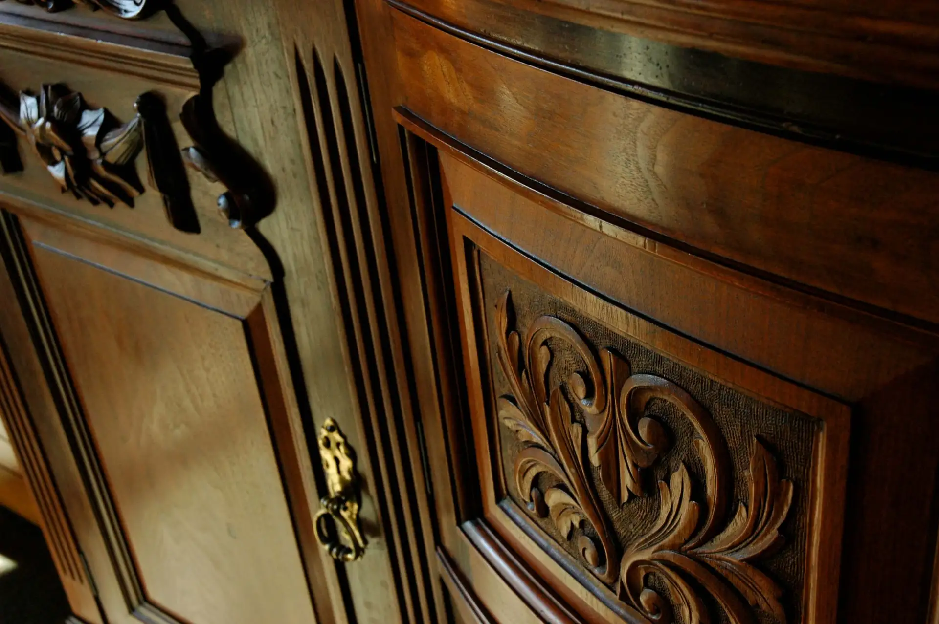 Close-up of a wooden cabinet with ornate carved details and a brass keyhole.