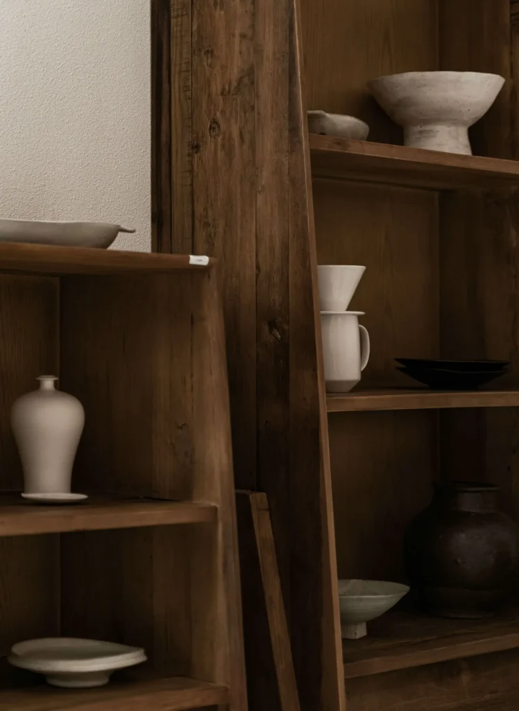 Wooden shelves with assorted ceramic dishes and vases in muted tones.